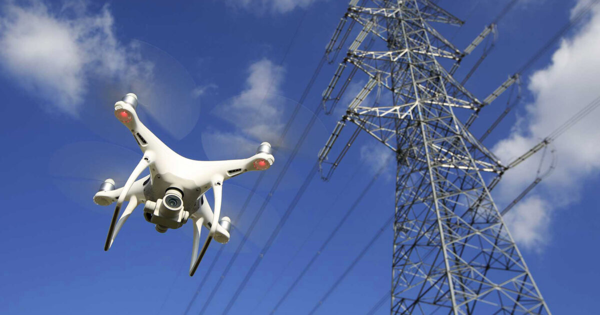 Drone flying near a high-voltage power transmission tower