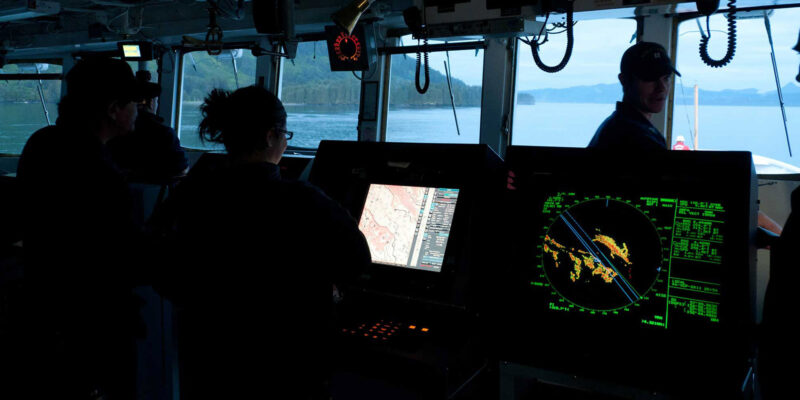 Ship bridge crew monitoring radar and navigation screens