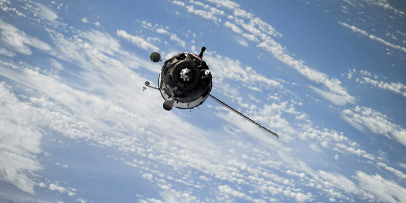 Spacecraft orbiting above Earth's clouds