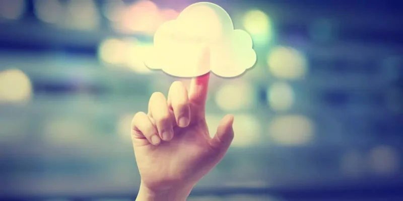 Hand touching a glowing white cloud icon against a blurred light background