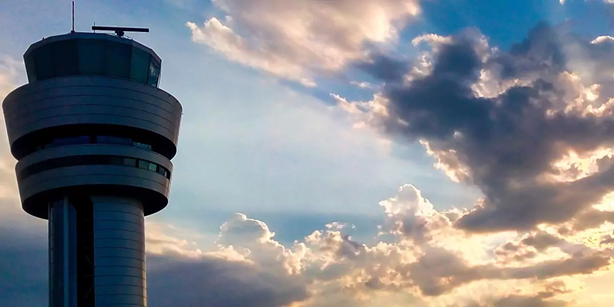 Airport control tower silhouetted against a dramatic sunset sky